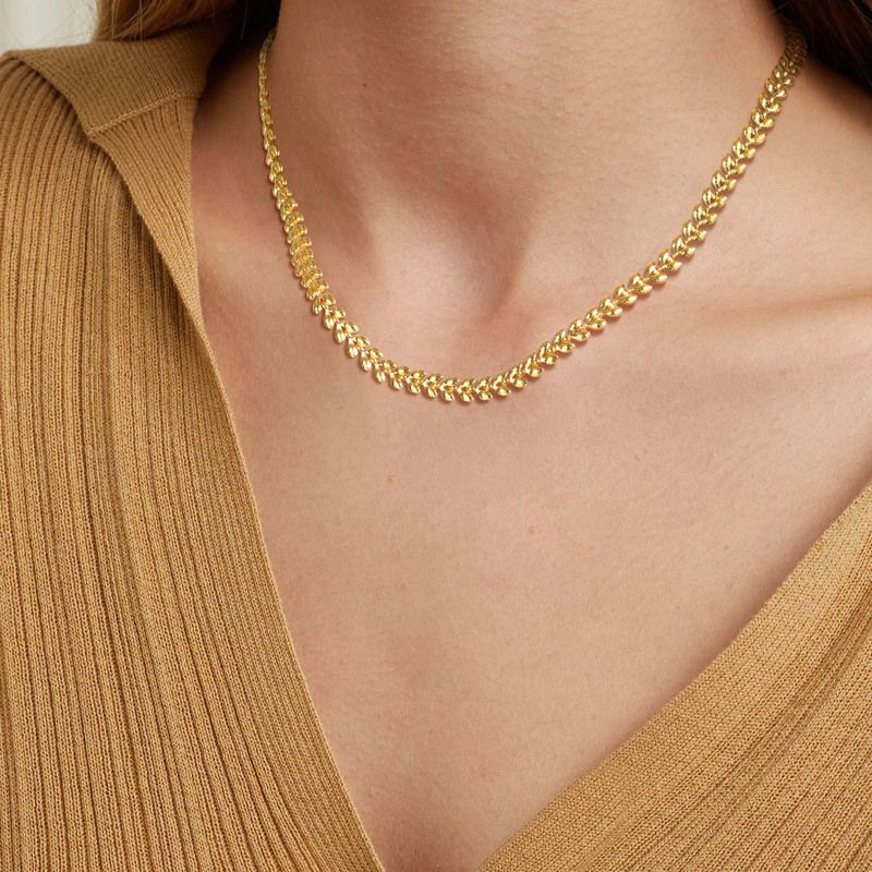 Collier chaîne à maillons olives dorés en acier inoxydable autour du cou d'une jolie femme - coloris plaqué or