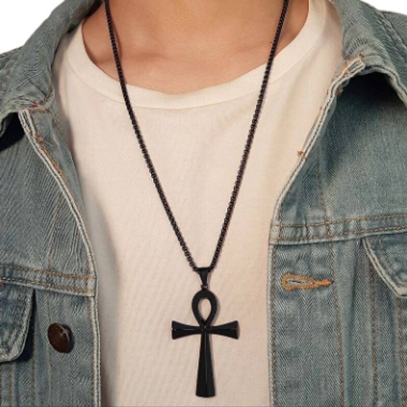 Collier croix avec pendentif égyptien ankh en acier inoxydable autour du cou d'un homme cool en veste en jean et tee-shirt blanc - coloris noir