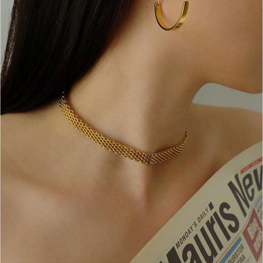 Bracelet ras de cou bismarck à maille résille doré en acier inoxydable autour du cou d'une jolie femme brune aux épaules dénudées