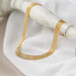 Bracelet ras de cou bismarck à maille résille doré en acier inoxydable présenté autour d'un pied de lampe de chevet couché de couleur blanc vieilli - bijou chic pour femme raffinée