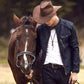 Cowboy marchant en compagnie de son fidèle compagnon, le cheval. Cet homme au chapeau arbore avec fierté une belle ceinture classique en cuir de vache pleine fleur de couleur noire, sa boucle ardillon en métal argenté lui permet de bien tenir son pantalon en jean.