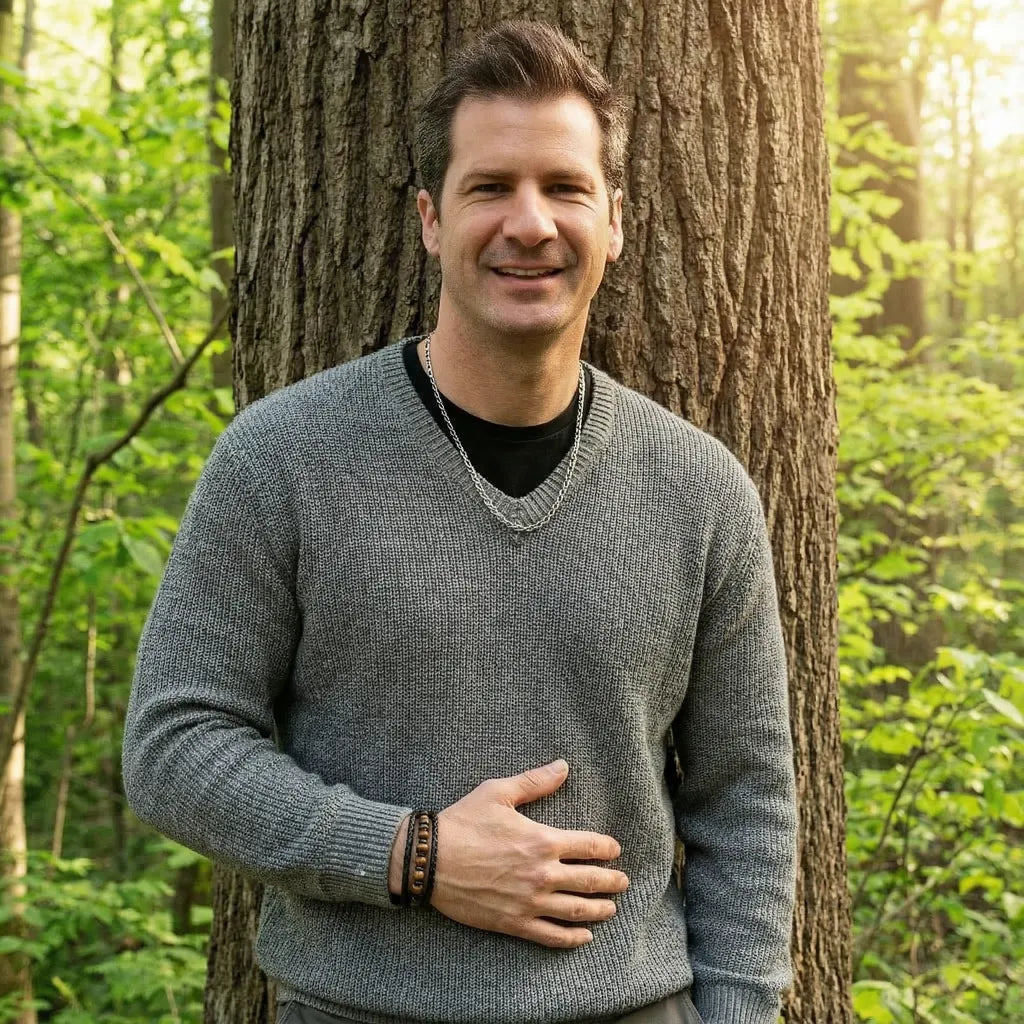 L'homme souriant, adossé contre un arbre de la forêt, porte le bracelet Talis multi-rangs. Le cuir souple noir tressé et l'œil de tigre apportent distinction et caractère à cette tenue grise.