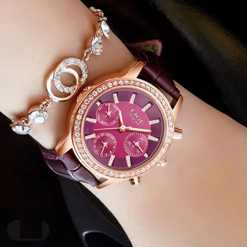 La Diana Cristal est une montre conçu pour les femmes élégantes, son cadran bordeaux est entouré d'une multitude de brillants, son boitier doré et son bracelet en cuir bordeaux apporte une touche de sophistication - elle est portée autour d'un poignet d'une femme arborant un superbe bracelet scintillant de mille feux.