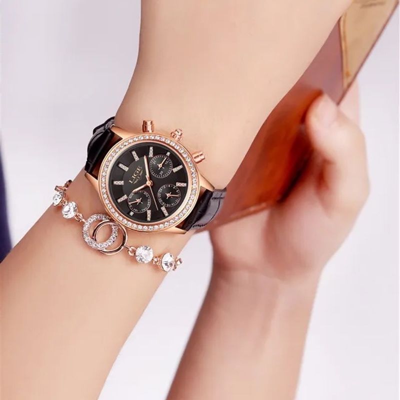 La Diana Cristal est une montre conçu pour les femmes élégantes, son cadran noir est entouré d'une multitude de brillants, son boitier, ses index et ses aiguilles dorés et son bracelet en cuir noir apporte une touche de sophistication - elle est portée autour d'un poignet d'une femme arborant un superbe bijou, un bracelet scintillant 