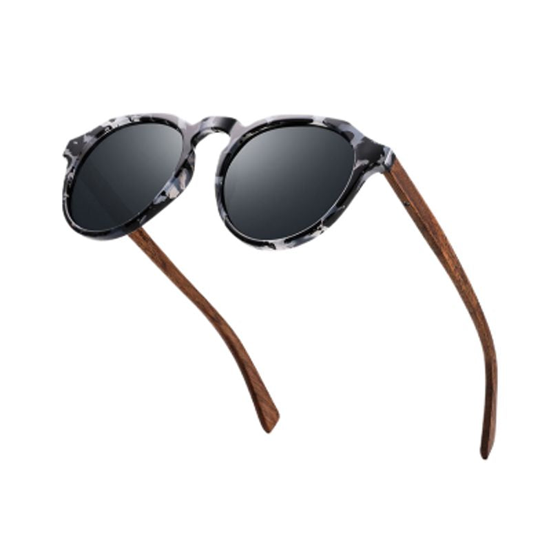 Vue de trois-quart de face d'une paire de lunettes de soleil rondes avec branches déployées en bois signé de la marque Oi Wood - monture unisexe en plastique PC noir et gris au motif écailles de tortue - coloris verres polarisés gris - UV400