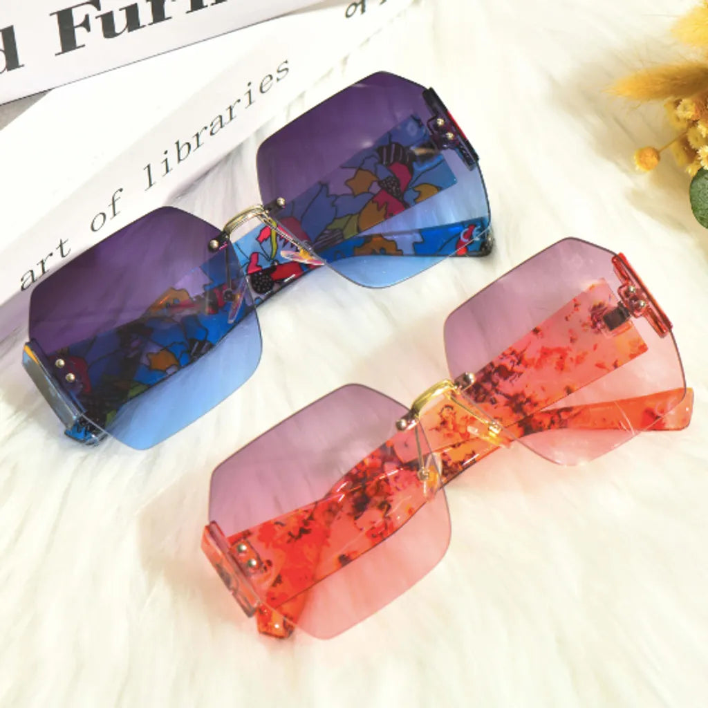 Lunettes de soleil tendance avec verres aux teintes mauves et roses, accentuées par des motifs artistiques et fleuris. L’association de couleurs et de motifs distinctifs fait ressortir un look artistique, parfait pour un style affirmé et original.