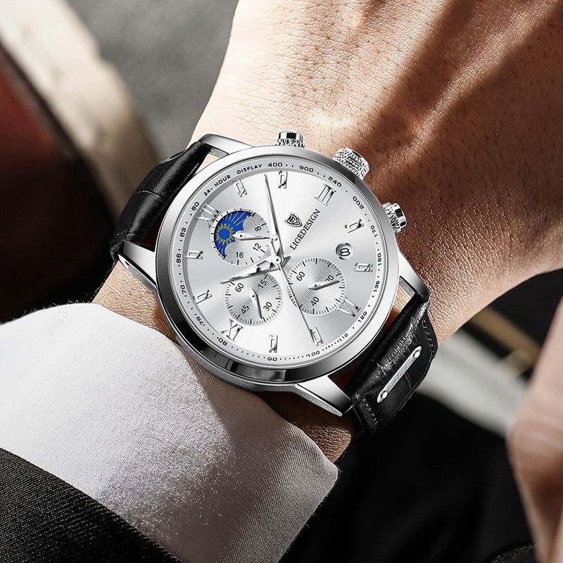 Montre Lige Design Pro pour homme avec chronographe et phase de lune avec bracelet en cuir noir, sur le poignet d'un homme qui consulte l'heure - coloris cadran blanc et boitier argenté