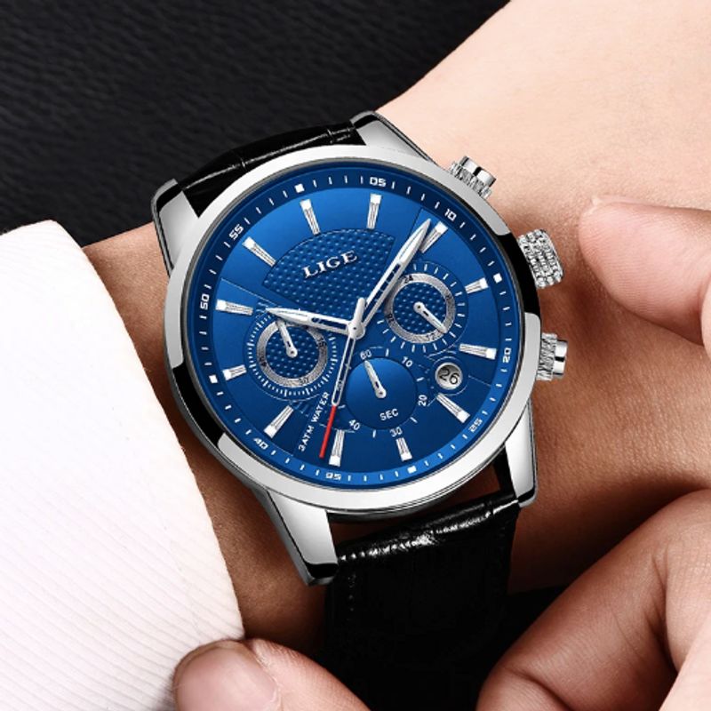 Montre Markus chronographe à quartz avec bracelet en cuir noir sur un poignet d'homme vêtu d'une chemise blanche, son boitier, ses aiguilles et ses index de couleur acier sont inoxydable - cadran coloris bleu