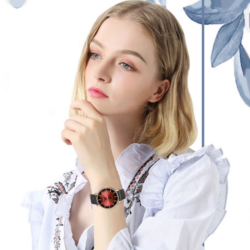 Montre top luxe avec un élégant bracelet gris en maille milanaise sur un poignet de jeune femme pensive - coloris rouge et or rose