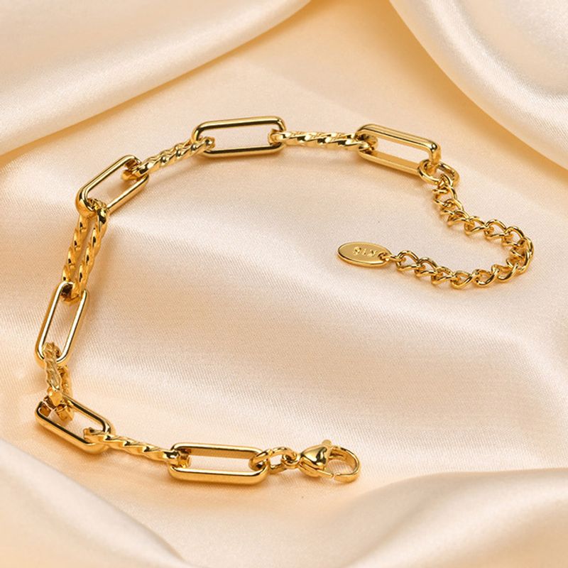 Bracelet à maillons trombones dorés en acier inoxydable plaqué or présenté sur un femme au chemisier blanc - courte vidéo
